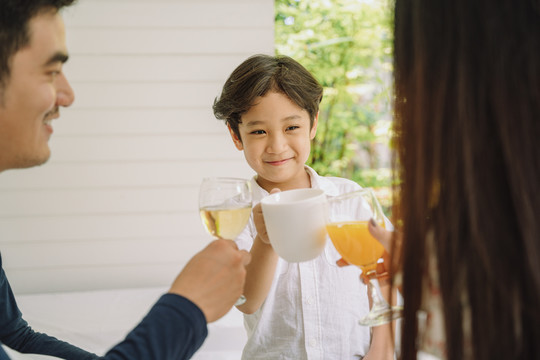 快乐快乐的亚洲小孩在午餐聚会上和大人一起举杯祝酒或喝奶。