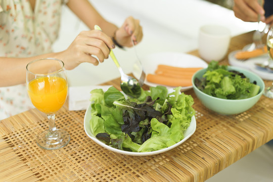 女人用叉子和勺子手吃蔬菜沙拉。健康的午餐和早午餐。