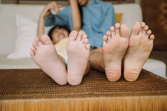 特写照片-小孩和母亲赤脚躺在床上。
