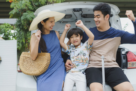 快乐快乐的亚泰家庭坐在一辆后备箱车上。旅行者家庭。