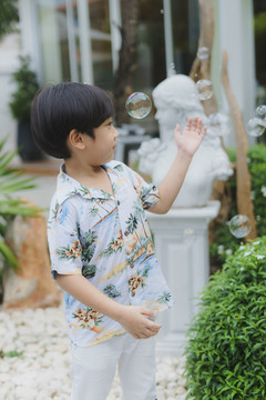 亚洲男孩在公园用肥皂泡熏烟的肖像。