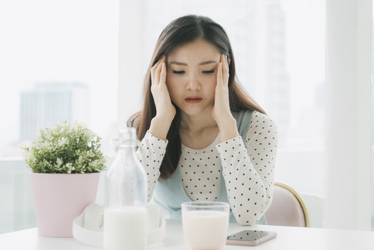 年轻漂亮的亚洲孕妇早餐后在家感到抑郁和头痛。