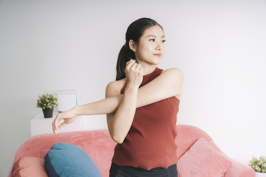 美丽的亚洲孕妇在家锻炼前伸展双臂。瑜伽。