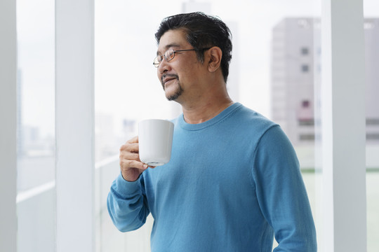 身着蓝色长袖衬衫、戴着眼镜、端着一杯咖啡的老人的画像。