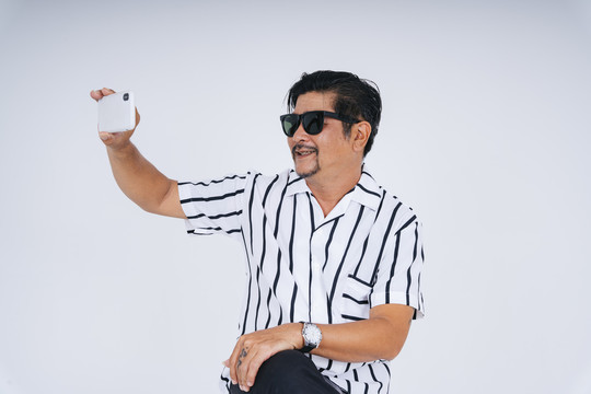 一位穿着白领衬衫戴墨镜手持智能手机的时髦老人的肖像。