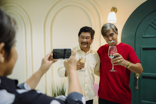 老年人用酒杯庆祝，用智能手机拍照的集体肖像。
