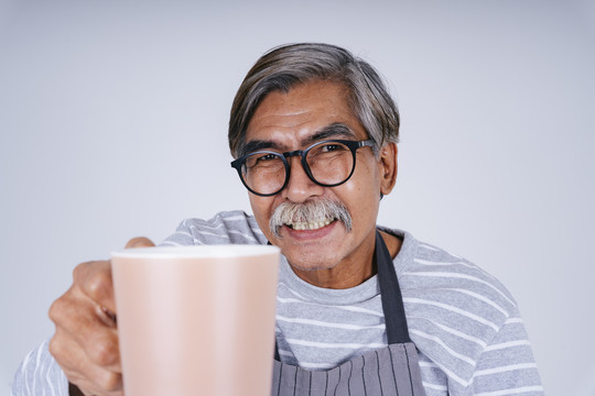 在白色背景上，一位老人拿着一杯咖啡。