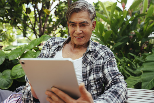 亚洲老年农民使用数字平板电脑销售农场产品。
