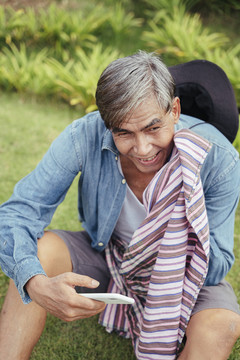 快乐的亚洲老年农民在农场使用智能手机。