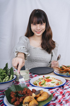 亚洲妇女用叉子在桌上吃辣猪肉球的画像。伊桑食品概念。