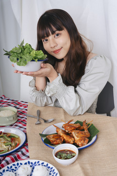 亚洲素食主义妇女手持一碗蔬菜和烤鸡一起吃的肖像。