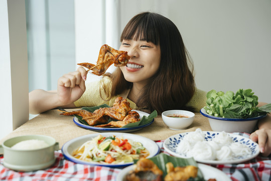 亚洲年轻女子喜欢吃烤鸡翅棒的画像。是一种食物概念。