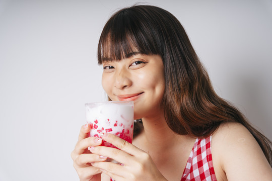 亚洲年轻女子手持一杯甜菱角甜点的画像。