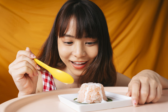 年轻的亚洲女人用黄色的勺子吃甜糯米。