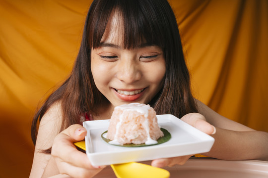 亚洲年轻女子手持一盘甜糯米的特写照片。