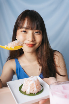 亚洲年轻女子用勺子吃甜糯米。