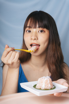 亚洲年轻女子用勺子吃甜糯米。