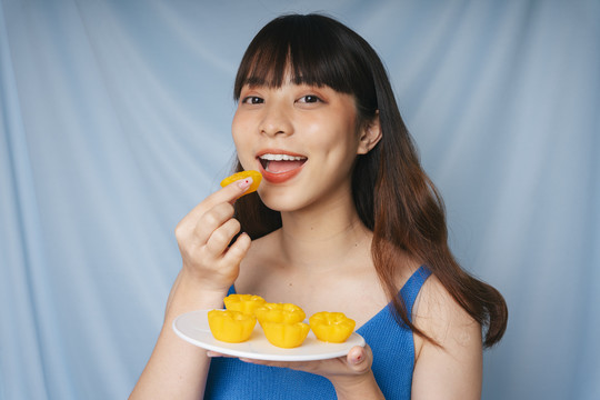 亚洲年轻女子吃泰国甜点金饼的特写镜头。