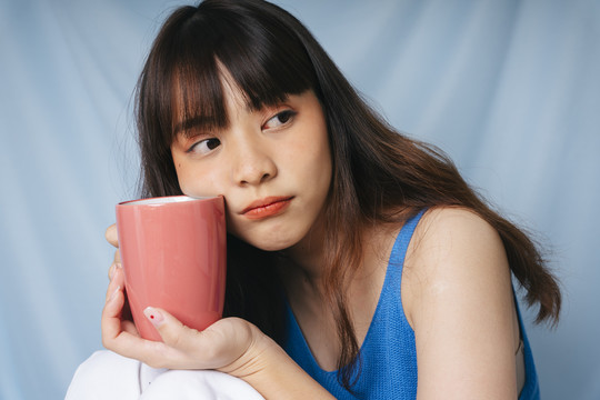 一个年轻的亚洲黑发女人拿着一杯咖啡的特写镜头。