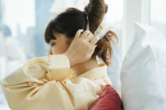 侧视图-年轻的亚洲黑发女子早上在床上戴着头巾