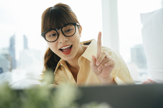 快乐快乐的年轻亚洲黑发女子戴着眼镜在电脑上做视频通话。