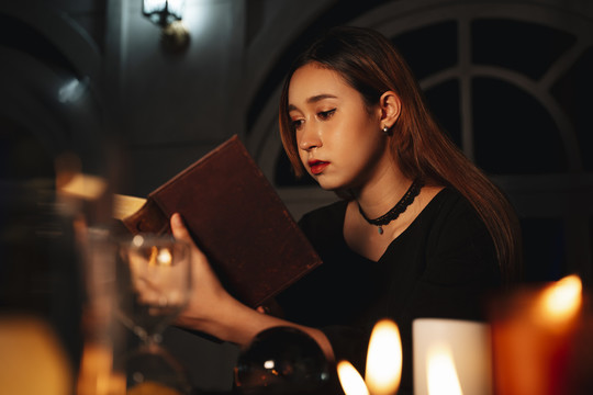 年轻漂亮的长发女算命师在读魔法书。