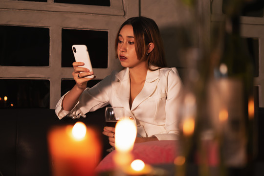 穿着正装的漂亮醉酒女晚上在家用手机喝红酒。