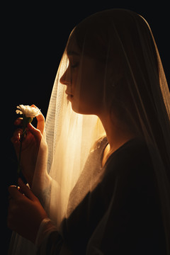 美丽的混血女子手持白色的花章在新娘身上。老婆鬼。黑色背景上的隔离。