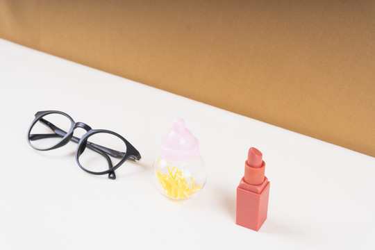 顶视图-眼镜，奶瓶和唇膏。家庭配件概念。