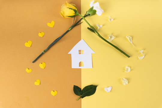 顶视图-房子剪纸和黄色和橙色背景上的花。