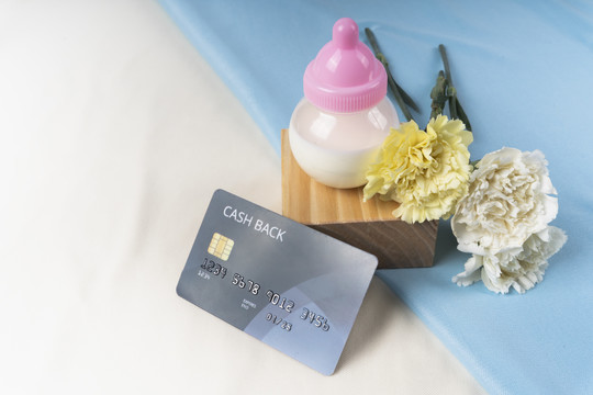 信用卡，一瓶牛奶和花在白色和蓝色的背景上。
