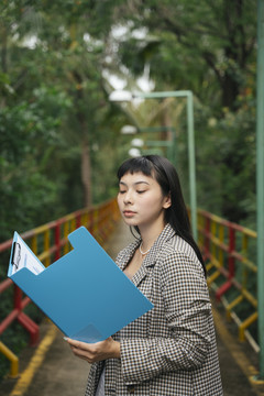 穿着正式衬衫的亚洲女商人正在阅读文件夹中的文件。