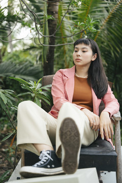 穿着正式衬衫在椅子上摆姿势的亚洲女商人。