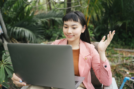 穿着正式衬衫的亚洲女商人在户外使用笔记本电脑。