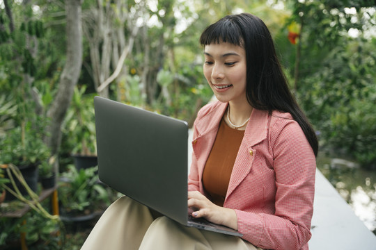 穿着正式衬衫在笔记本电脑上工作的亚洲女商人。