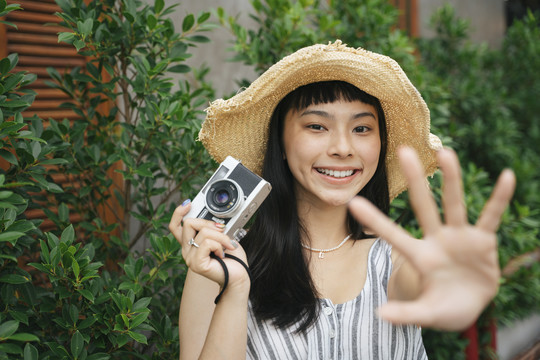 用老式相机拍摄亚洲年轻女性的时尚肖像。度假胜地的美丽摄影师。