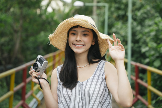 用老式相机拍摄亚洲年轻女性的时尚肖像。度假胜地的美丽摄影师。