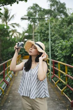 用老式相机拍摄亚洲年轻女性的时尚肖像。度假胜地的美丽摄影师。