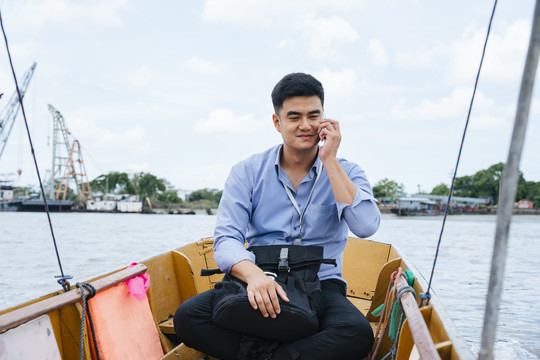 在泰国曼谷，一位亚洲商人正在乘船旅行。