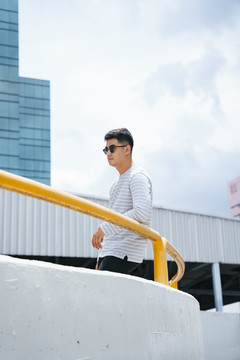 时尚的亚洲成年男子在城市里戴太阳镜的画像。