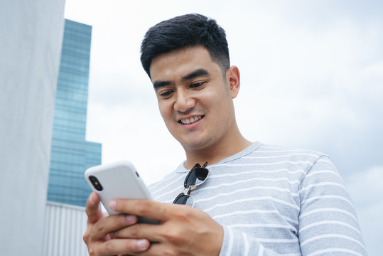 亚洲男人在城市里使用智能手机的特写照片。