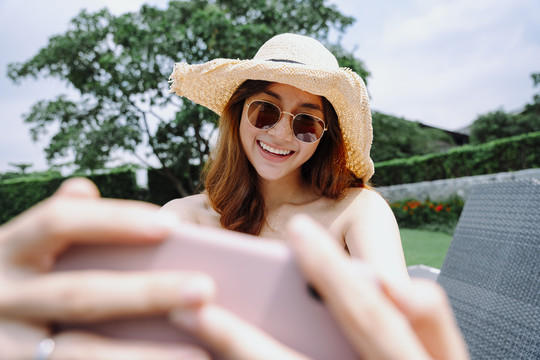 美丽的亚洲女旅行者用智能手机上网或自拍。