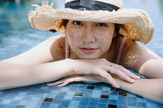 美丽的亚洲女游客戴着帽子在游泳池里放松的特写镜头。