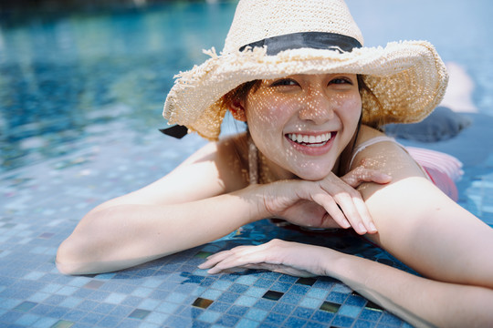 美丽的亚洲女游客戴着帽子在游泳池里放松的特写镜头。