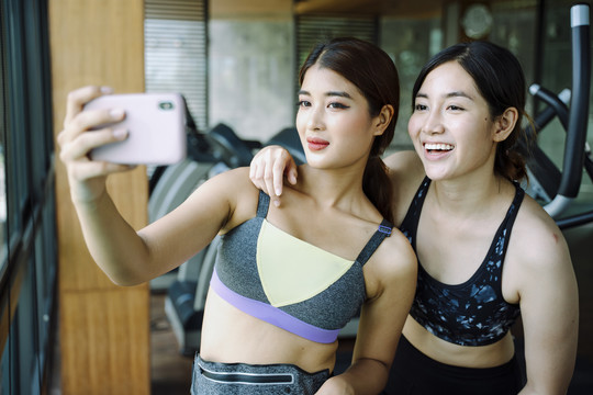 美丽健康的女人穿着运动内衣在健身房用智能手机自拍。