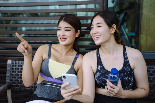 美丽健康的女性在运动后在休息室使用智能手机。