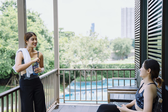 美丽健康的女人一起运动后在阳台上和朋友聊天。