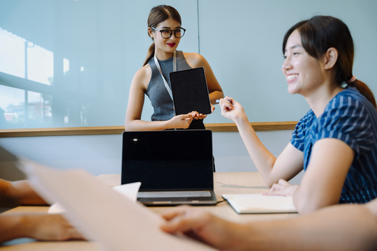 亚洲女商务人士在会议室用数字笔记本电脑讲解战略计划。