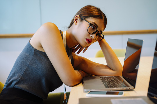 亚洲女商人戴着眼镜厌倦了工作和看笔记本电脑。