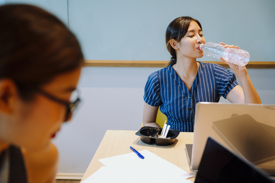亚洲女商人在办公室喝水和吃午餐。